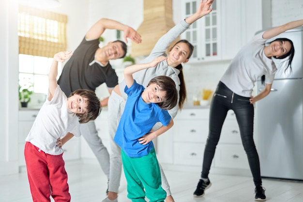 Joyeuse famille latine faisant de l'exercice, s'entraînant le matin ensemble à la maison. Famille, concept sportif. Mise au point sélective sur les jumeaux