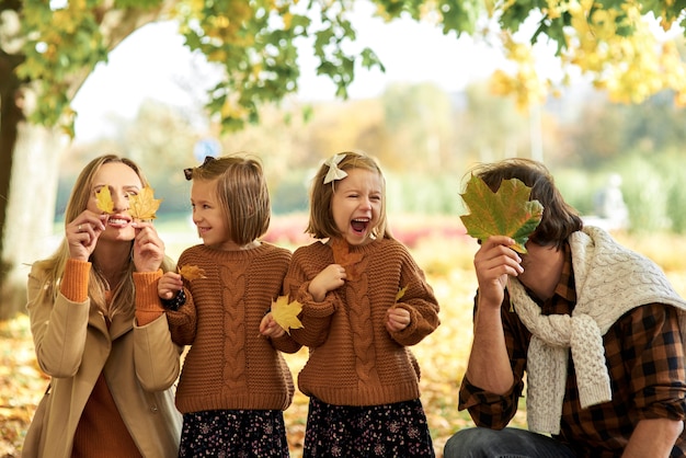 Joyeuse famille s'amusant avec des feuilles d'automne dans les bois