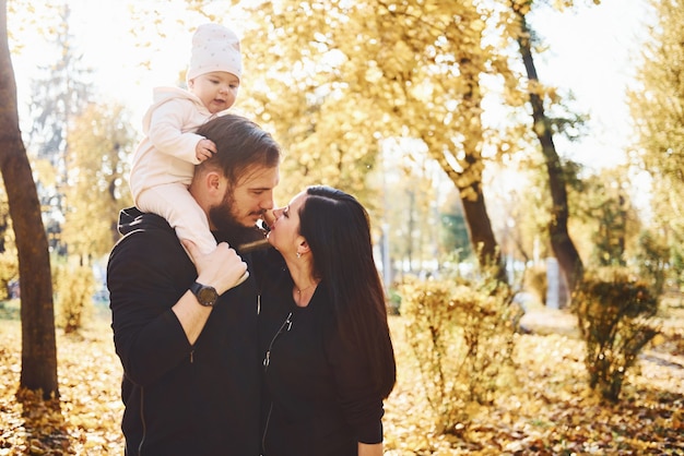 Joyeuse famille s'amusant avec leur enfant dans un magnifique parc d'automne.