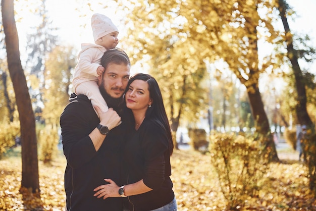 Joyeuse famille s'amusant avec leur enfant dans un magnifique parc d'automne.