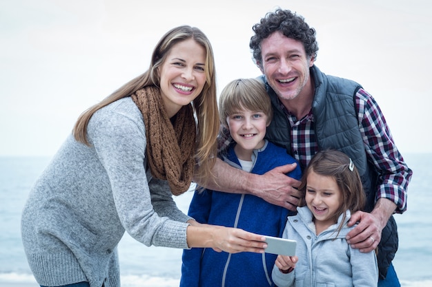 Joyeuse famille avec téléphone portable profitant de la plage