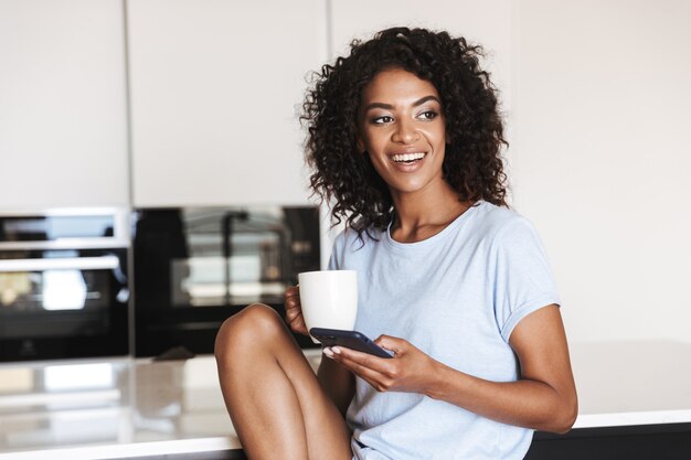 Joyeuse femme africaine à l'aide de téléphone mobile