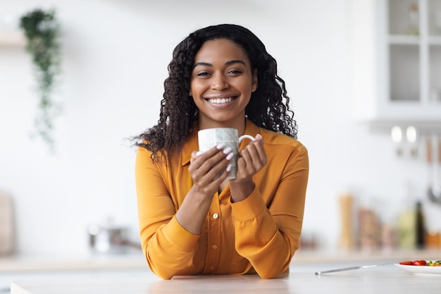 Joyeuse femme afro-américaine buvant du thé à la maison