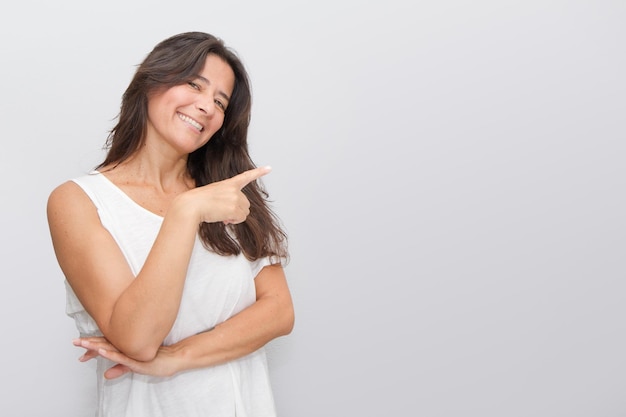 Joyeuse femme d'âge moyen souriante et heureuse pointant vers la droite