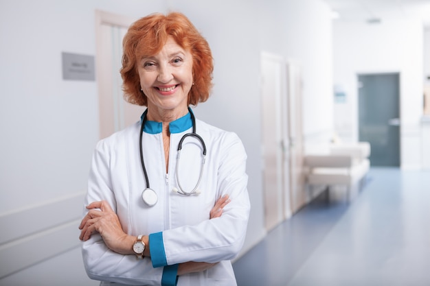 Joyeuse femme âgée médecin souriant à la caméra