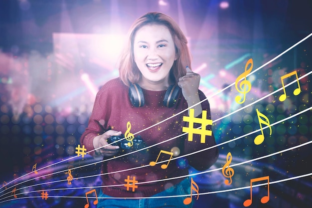 Joyeuse femme asiatique jouant à des jeux vidéo portant des écouteurs et tenant un joystick