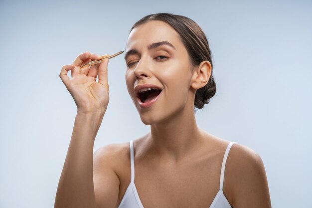 Joyeuse femme brune faisant des procédures de beauté par elle-même