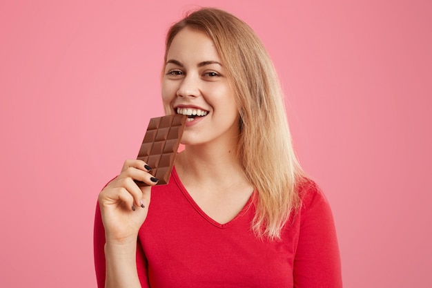 Joyeuse femme européenne détient une barre de chocolat