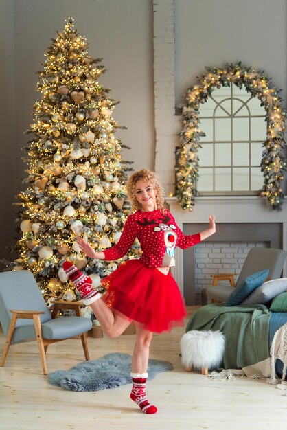 Joyeuse femme joyeuse dans un chandail rouge, célébrant les vacances de Noël d'hiver