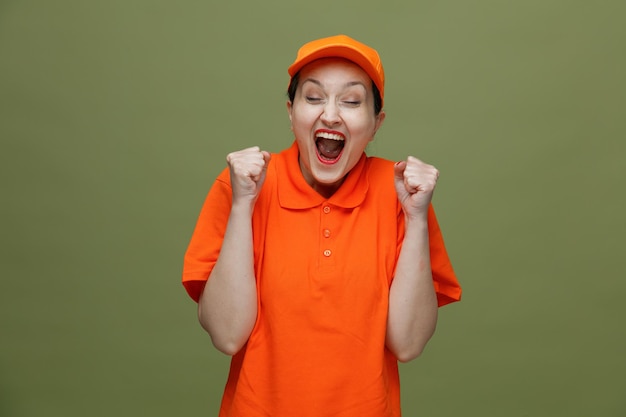 Joyeuse femme de livraison d'âge moyen portant l'uniforme et la casquette faisant un geste oui avec les yeux fermés isolé sur fond vert olive