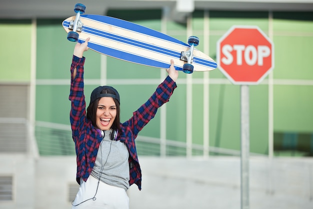 Photo joyeuse femme posant avec longboard