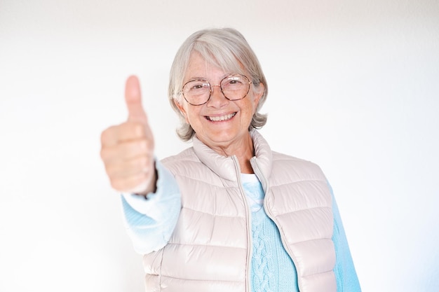 Joyeuse femme senior aux cheveux blancs regardant la caméra montrant le signe ok avec le pouce vers le haut