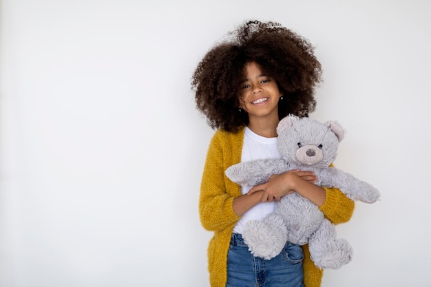 Joyeuse fille afro-américaine posant avec son jouet sur blanc