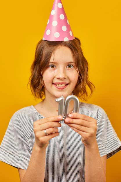 Joyeuse fille d'anniversaire positive de dix ans en chapeau de fête