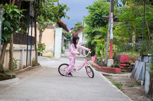 Joyeuse fille enfant asiatique gaie, faire du vélo