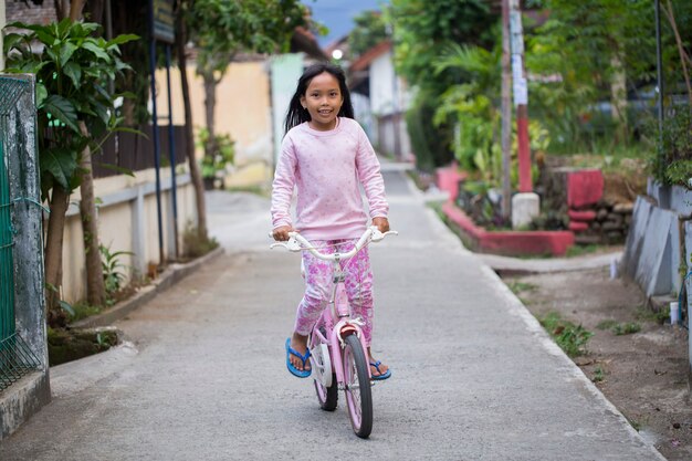 Joyeuse fille enfant asiatique gaie, faire du vélo