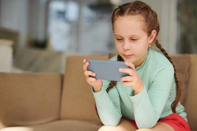 Joyeuse fille jouant au jeu sur smartphone