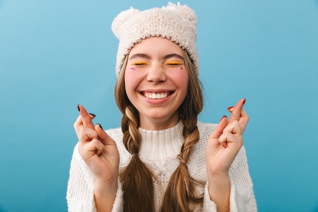 Joyeuse fille portant un chandail debout isolé, les doigts croisés