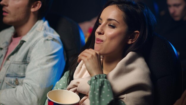 Joyeuse fille riant au cinéma Joyeuse femme regardant la comédie dans le hall sombre