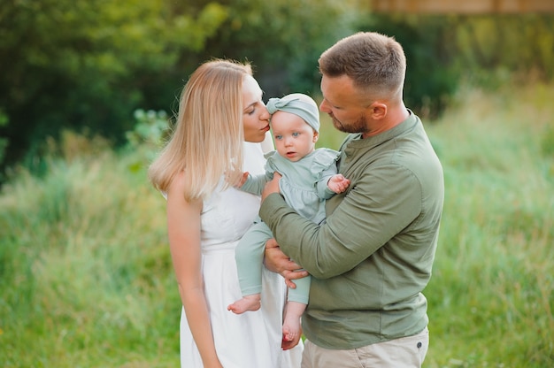 Joyeuse jeune famille passant du temps ensemble à l'extérieur dans la nature verdoyante.