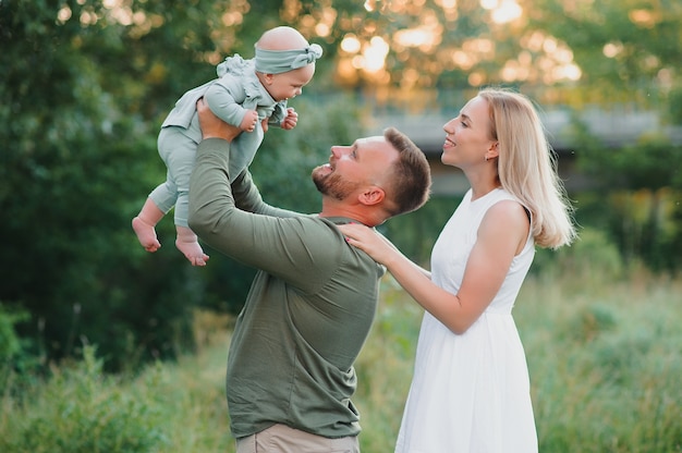 Joyeuse jeune famille passant du temps ensemble à l'extérieur dans la nature verdoyante.