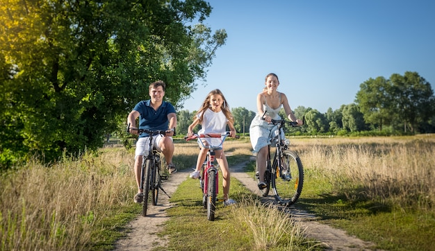 Joyeuse jeune famille à vélo au pré. Concept de sport familial