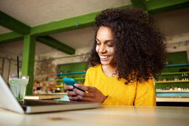 Joyeuse jeune femme à l&#39;aide de téléphone portable dans un café