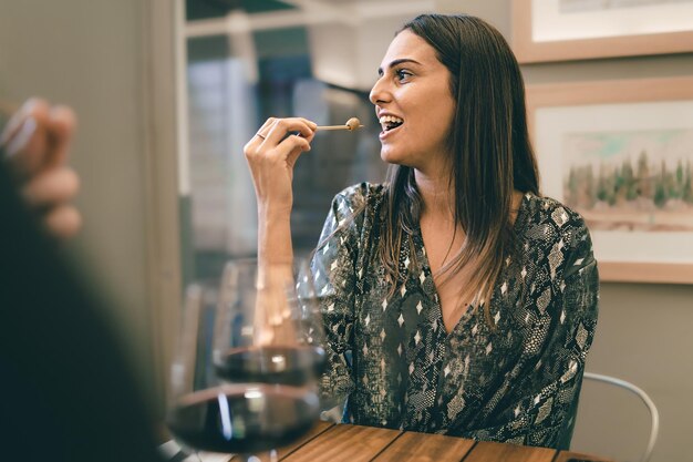 Joyeuse jeune femme assise à la table du restaurant devant une personne méconnaissable