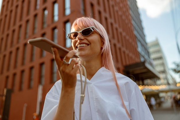 Joyeuse jeune femme ayant une conversation téléphonique à l'extérieur