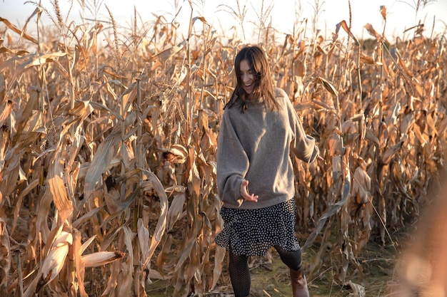 Joyeuse jeune femme dans un champ de maïs en automne.