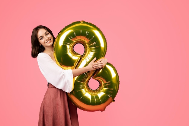 Joyeuse jeune femme européenne tenir le ballon numéro 8 profiter des vacances de printemps anniversaire de la journée de la femme