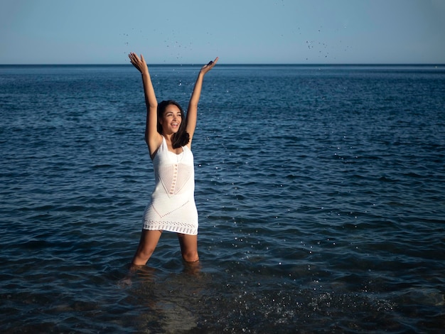 Joyeuse jeune femme hispanique éclaboussant de l'eau en mer