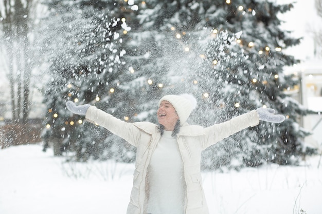 Joyeuse jeune femme jouant avec de la neige dans la forêt