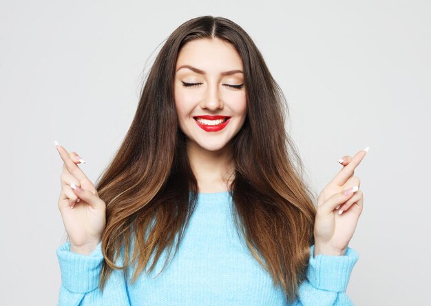 Joyeuse jeune femme serre les dents lève les doigts croisés fait un souhait souhaitable