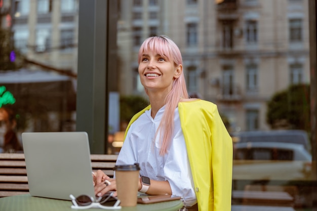 Joyeuse Jeune Femme Utilisant Un Ordinateur Portable Au Café En Plein Air