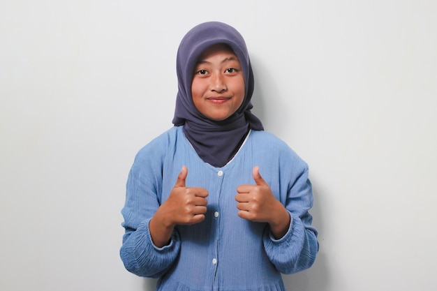 Joyeuse jeune fille asiatique en hijab montrant deux pouces vers le haut