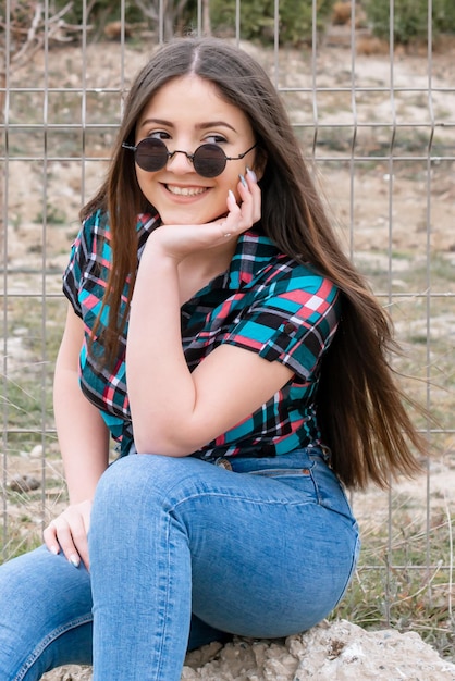 Joyeuse jeune fille assise sur le rocher et souriant