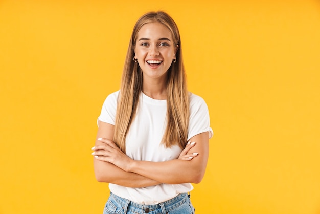 Joyeuse jeune fille portant des vêtements décontractés debout isolée sur un mur jaune, les bras croisés