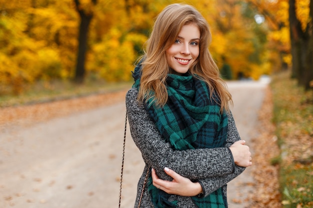 Joyeuse jolie belle jeune femme avec manteau gris à la mode