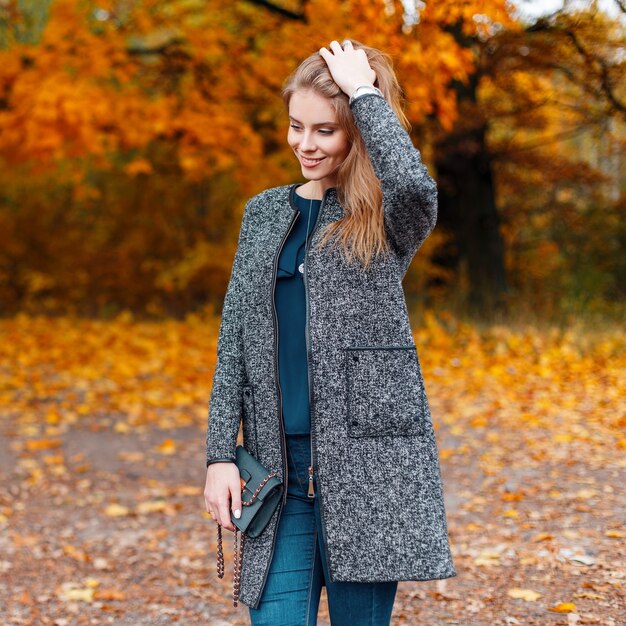 Joyeuse jolie belle jeune femme avec manteau gris à la mode