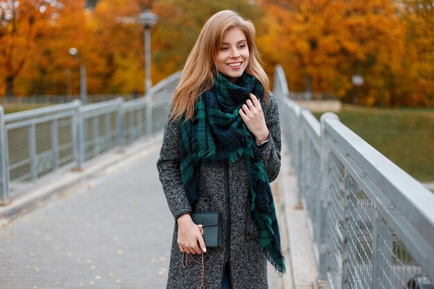 Joyeuse jolie belle jeune femme avec manteau gris à la mode