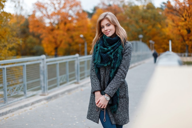 Joyeuse jolie belle jeune femme avec manteau gris à la mode