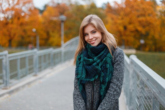 Joyeuse jolie belle jeune femme avec manteau gris à la mode