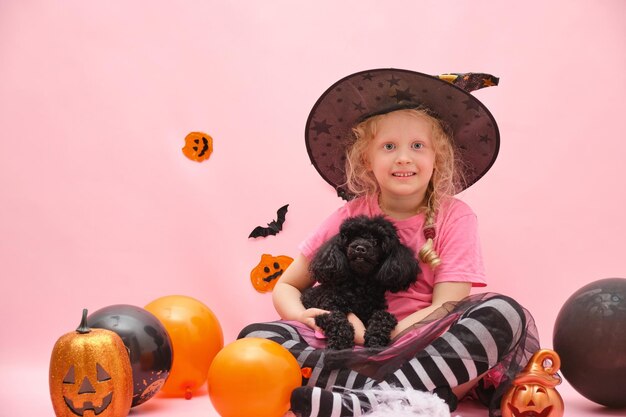 Joyeuse jolie fille et petit mini caniche noir sur fond de paysage d'halloween