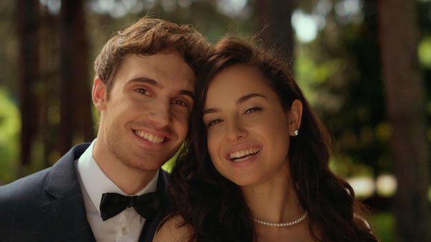 Joyeuse mariée et le marié regardant la caméra dans le jardin