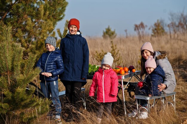 Joyeuse mère avec des enfants lors d'un pique-nique. Famille en vacances avec des fruits en plein air.