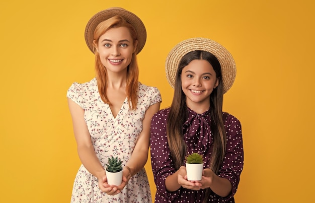 Joyeuse mère et fille avec plante en pot sur fond jaune