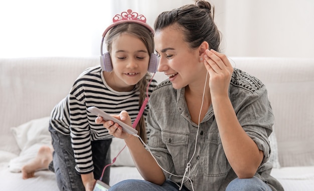 Photo joyeuse mère et fille se reposent à la maison, écoutant de la musique avec des écouteurs. concept d'une famille heureuse et de relations amicales.