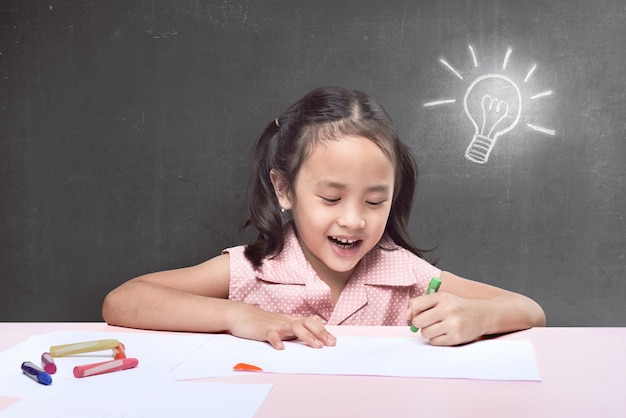 Joyeuse petite fille asiatique ayant une nouvelle idée pour dessiner avec un crayon