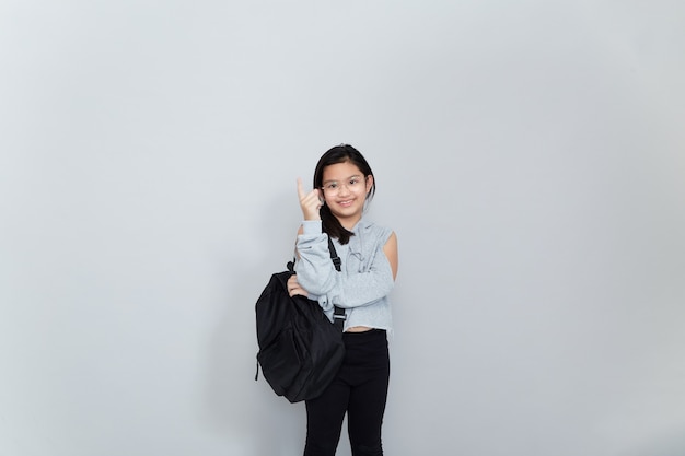 Une joyeuse petite fille asiatique souriante porte un sac d'école